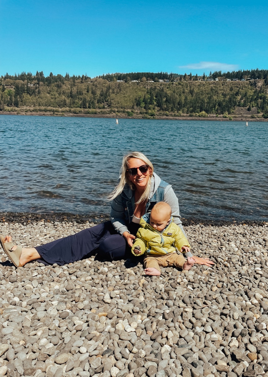 Kennady sitting on a rocky beach with her son, Henry